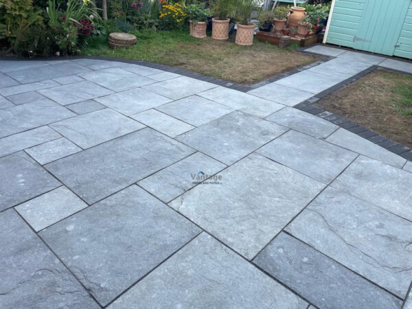 Patio with Silver Limestone Slabs and Charcoal Paved Border in…